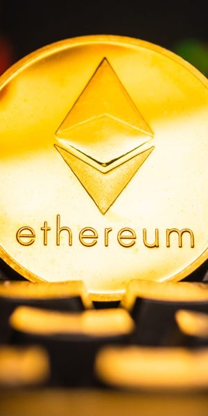 A golden coin with ethereum symbol on computer keyboard with stock graph background.